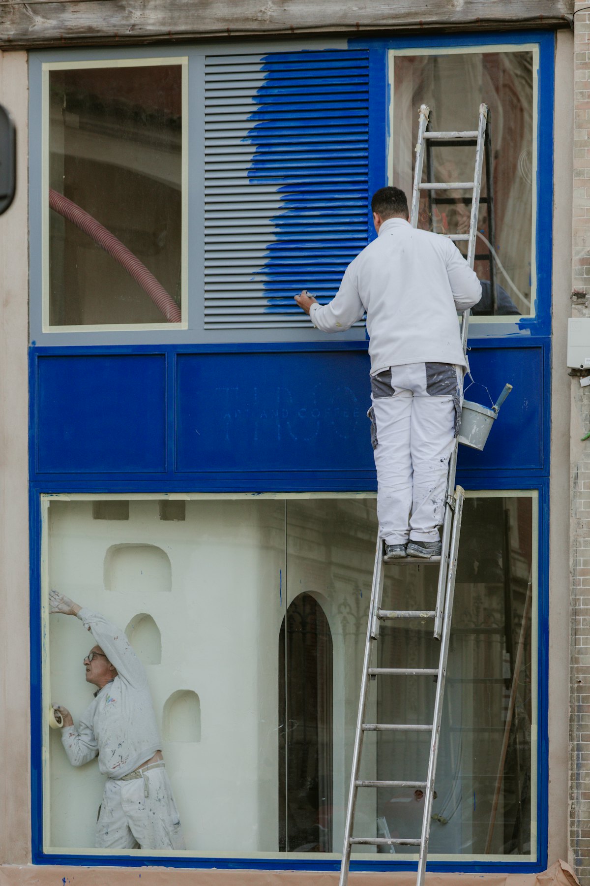Painter on a ladder painting exterior window trim